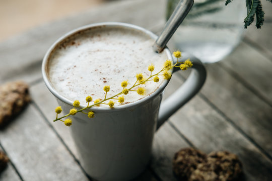 Cup of Cappuccino with cinnamon and mimoza on wooden table. Spring concept
