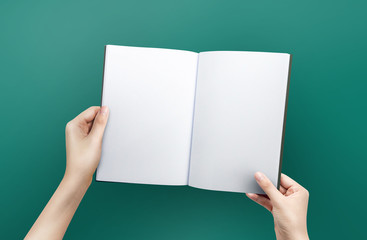 Woman hands holding a blank book for reader with copy space at green background