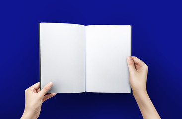 Woman hands holding a blank book for reader with copy space at blue background