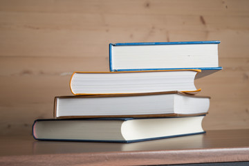 Stack of books on wooden table.