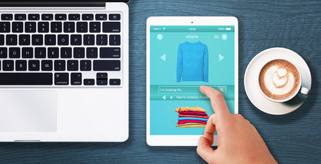 Man shopping clothes with tablet.  Top view desk scene with coffee and laptop