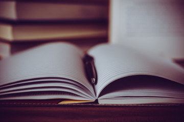 Pen on open book with wooden background. Education concept.