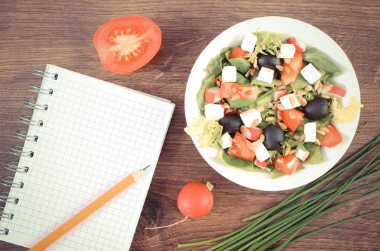 Vintage photo, Fresh greek salad with vegetables and notepad for writing notes, healthy nutrition