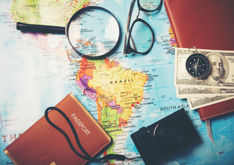 Top view of Money,Magnifier,compass,notebook and camera on world map background. Traveling concept.