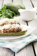 Stuffed zucchini with ground chicken and cilantro on the white plate. Spring menu. Green squash. Healthy lifestyle. Green veggies. Easter dinner.