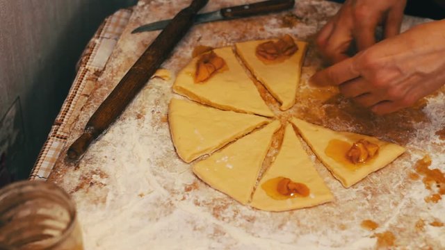 A woman puts on fresh pieces of dough apricot jam