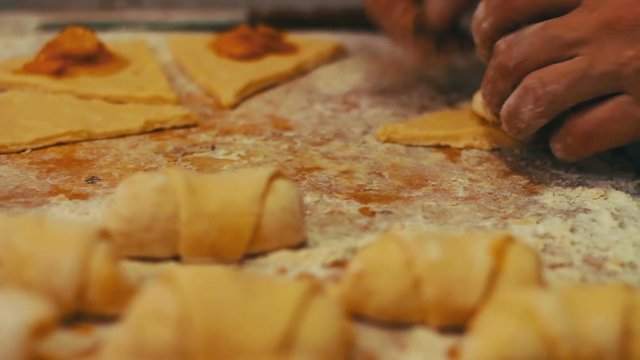 A woman puts on fresh pieces of dough apricot jam