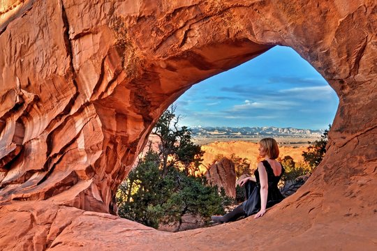 Woman by natural arch in Arches National park. Partition Arch. Devil's Garden. Moab. Utah. United States.