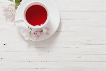 Red tea with flowers on white wooden background