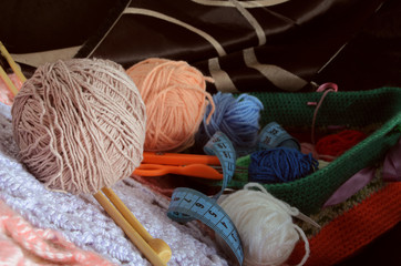 Ball of wool and bamboo spokes in the foreground against the background of accessories to knitting.