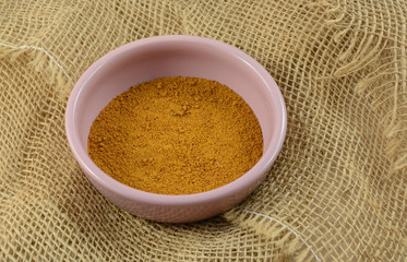 Ground mace spice in pink condiment dish on burlap