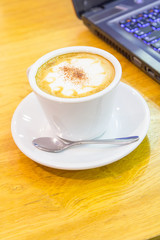 hot coffee on the table and laptop on background