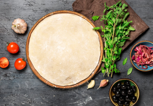 Ingredients for cooking vegetarian pizza on a dark stone surface