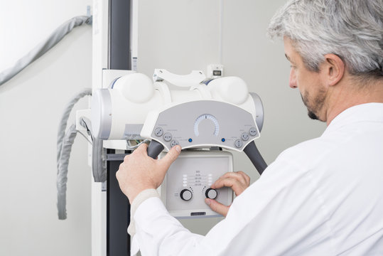 Male Radiologist Adjusting The Controls On X-ray Machine