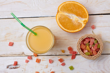 A whole orange with a glass of orange juice on a white wooden background. View from above.