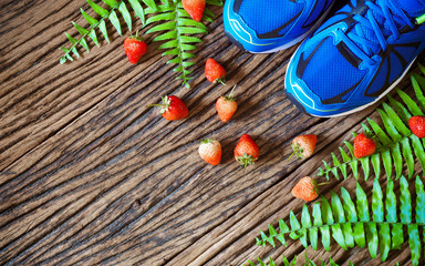 Fitness, healthy eating and active lifestyles Concept,  sport shoes and strawberries on grunge wood background. top view with copy space for text.