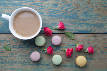 Macaroons, coffee and rose on green wooden background. Top view. Flat lay
