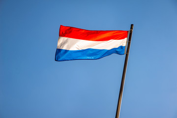 Fototapeta na wymiar Flag of Luxembourg fluttering on a metal flagpole 
