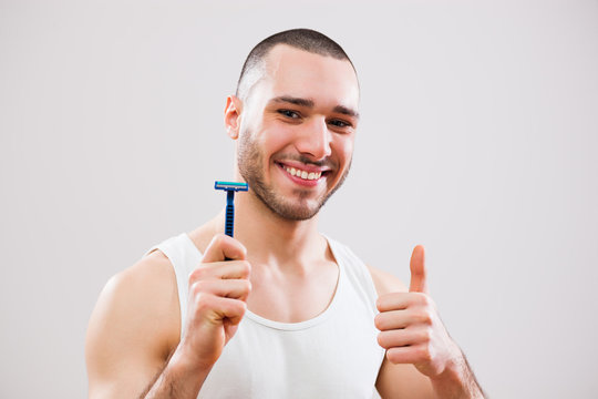 Young man is holding razor and he is going to shave his beard.