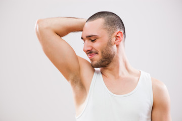 Young man is smelling his armpit after shower.