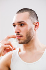 Young man is applying nose spray.