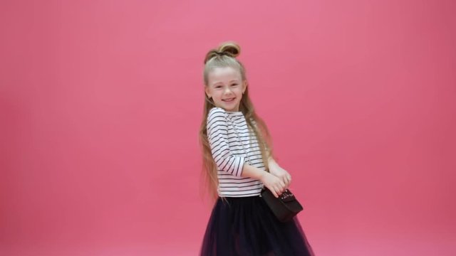 cute young girl laughs on a pink background
