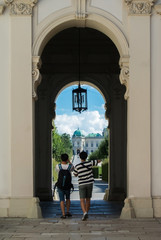 VIENNA, AUSTRIA - JULY 29, 2016: Two tourists, making photo at the entrance of Belevedere palace in Vienna, Austria, on sunny summer day.