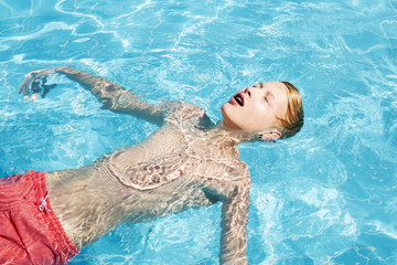 Teenager in red swimming trunks relaxes in the pool