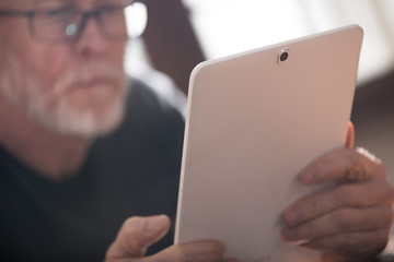 Senior man using his tablet, hard light effect