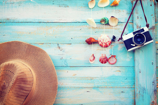 Summer background - The concept of leisure travel in the summer on a tropical beach seaside. retro camera with straw hat hanging on wood wall background.  vintage color tone styles.