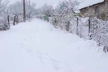 Winter landscape with path in deep snow on a street of small Ukrainian village.