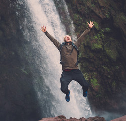 Happy adventurer jumping near Ouzoud waterfall in Morocco.