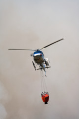 h&eacute;licopt&egrave;re dans la fum&eacute;e au dessus d'un feu avec un sac d'eau