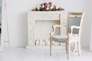 Chair and fireplace with bouquet of flowers on it.