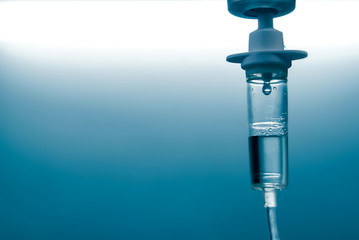 close up of a slow intravenous drip with a blurred lit neon in the background in a hospital room