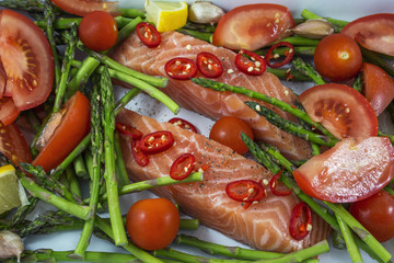 Two tasty pieces of salmon with green asparagus, tomato and red pepper