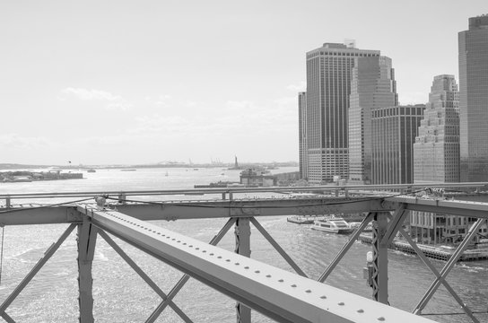Fototapeta Manhattan skyline with the Statue of Liberty in the distance, seen from the Brooklyn Bridge in black and white