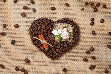 Obraz na płótnie Canvas Heart of coffee beans with artificial flowers