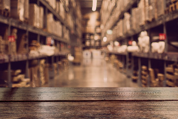 Empty dark wood table top on blurred warehouse.