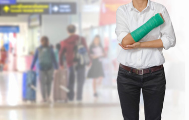 Injured woman with green cast on hand and arm on traveler in motion blur in airport interior background, ,body injury concept