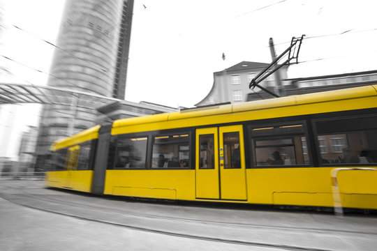 speeding yellow tram with black and white city background