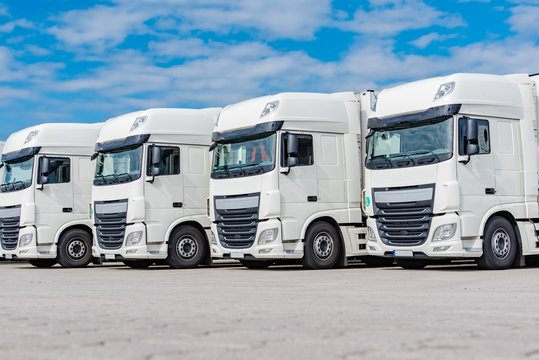 Transportgewerbe - Vier weiße LKW`s auf einen Speditionshof in Reihe geparkt