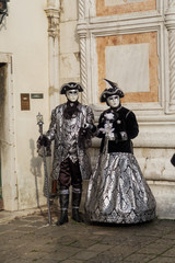 Fototapeta na wymiar Venice, Italy carnival mask and costume poses. Masked persons in traditional costume pose at a Venetian square during the Venice 2017 Carnival. 