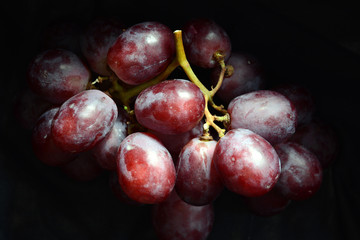 A bunch of ripe, rose grapes at black background - close-up