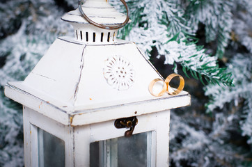 Naklejka premium Gold wedding rings lie on a white candlestick lamp