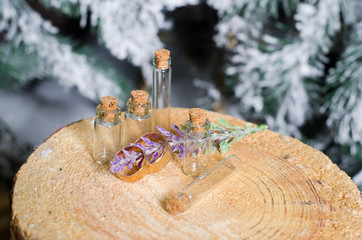 Gold wedding rings lie on a natural sawing wood near the empty vials and lilac closeup