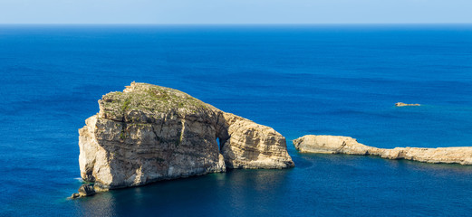 Gozo, Malta - The famous Fungus Rock on the island of Gozo on a beautiful hot summer day with crystal clear blue sea water and sky