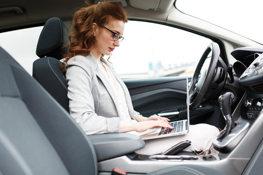 A businesswoman, always on the move, diligently prepares for an upcoming meeting while seated in her car.