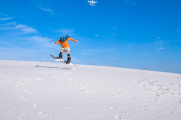 Naklejka na ściany i meble Drone shoots a man who does tricks on a snowboard