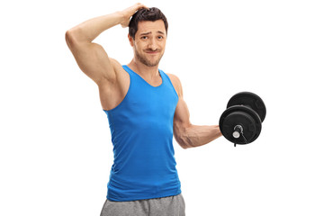 Tired guy lifting a dumbbell and holding his head